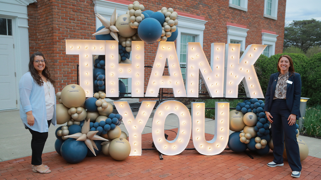 advancement events team standing in front of marquee thank you sign